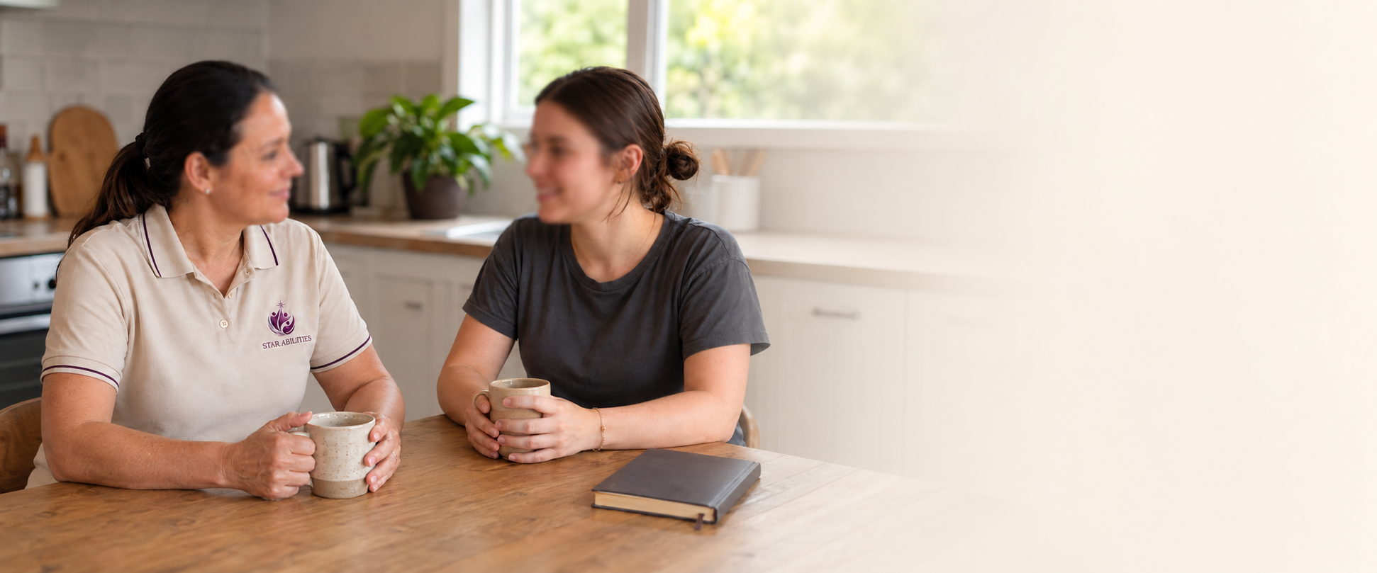 Star Abilities support worker having a cup of tea and a conversation with a client at a kitchen table
