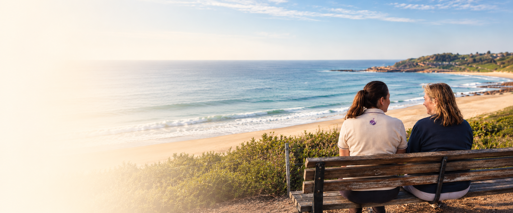 A Star Abilities support worker and a client sitting on a bench looking out over a Sydney beach